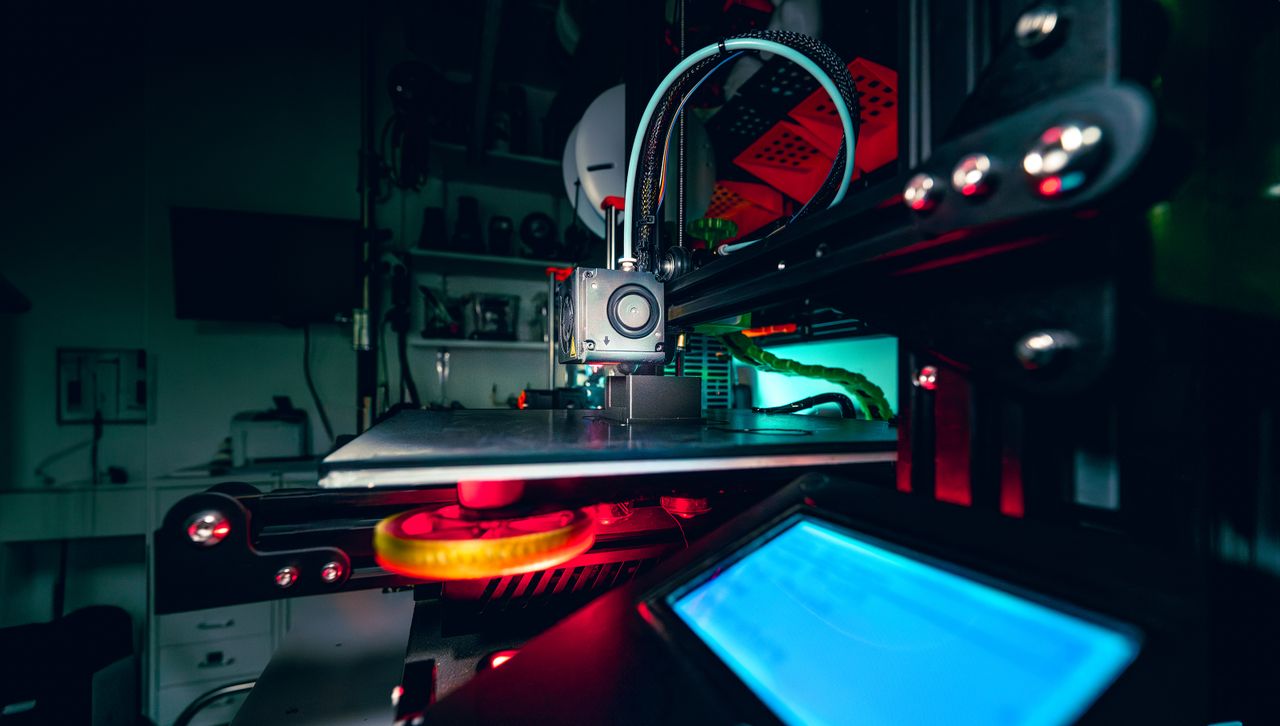 Detailed view of a 3D printer operating in a dimly lit workshop.